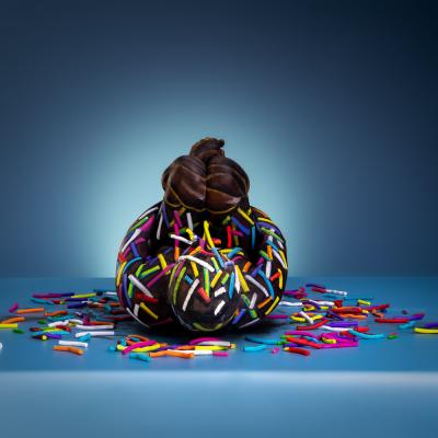 Bodypainting-Illusion eines Schokodonuts mit bunten Streuseln.