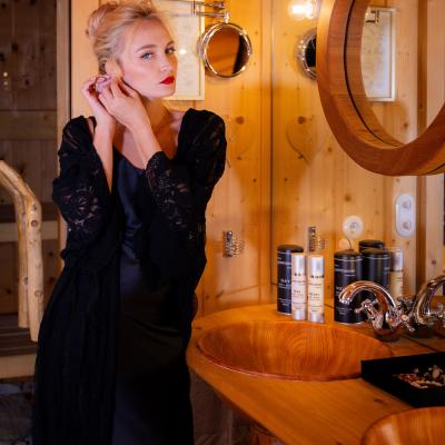 Blonde Frau legt Ohrringe ab in Hotelbadezimmer aus Holz