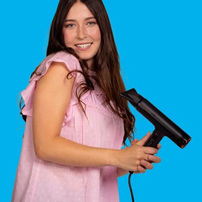 Frau vor blauem Hintergrund mit Fön in der Hand