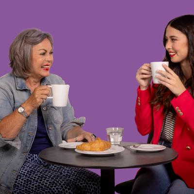 Zwei Frauen sitzen zusammen und trinken Kaffe und essen ein Croissant.