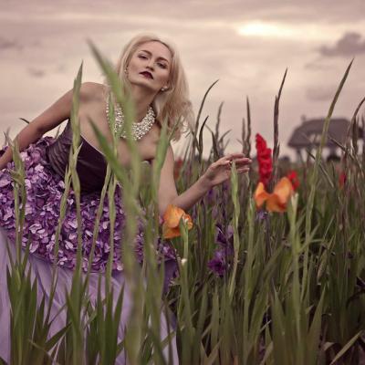 Blonde Frau mit rosa Prinzessinnenkleid steht in buntem Blumenfeld