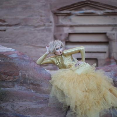 Blonde Frau post vor Steinmauer in gelben Kleid