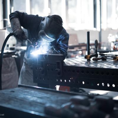 Mann schweißt Metall auf einer Werkbank