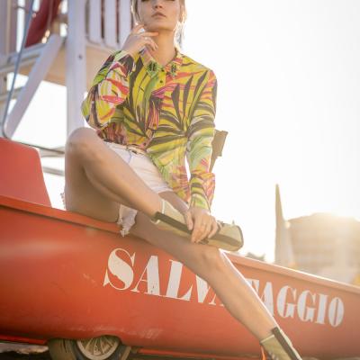 Blonde Frau sitzt am Strand von Miami auf einem Rettungschwimmerbot an Land