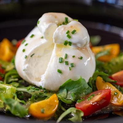 Schwarzer Teller Tomaten und Kräutern und Büffelmozzarella drauf