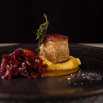 Schweinsbraten auf Kartoffelpüree mit Rote RübenSalat auf schwarzem Teller